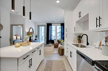 A kitchen with white cabinets and a sink and a living room